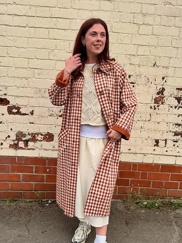 Person wearing a red and white checkered coat against a brick wall.