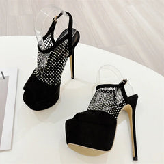 Black high-heeled shoes with rhinestone detailing on a white surface.