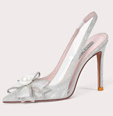 High-heeled shoe with decorative bow and pearl detail on a light gray background