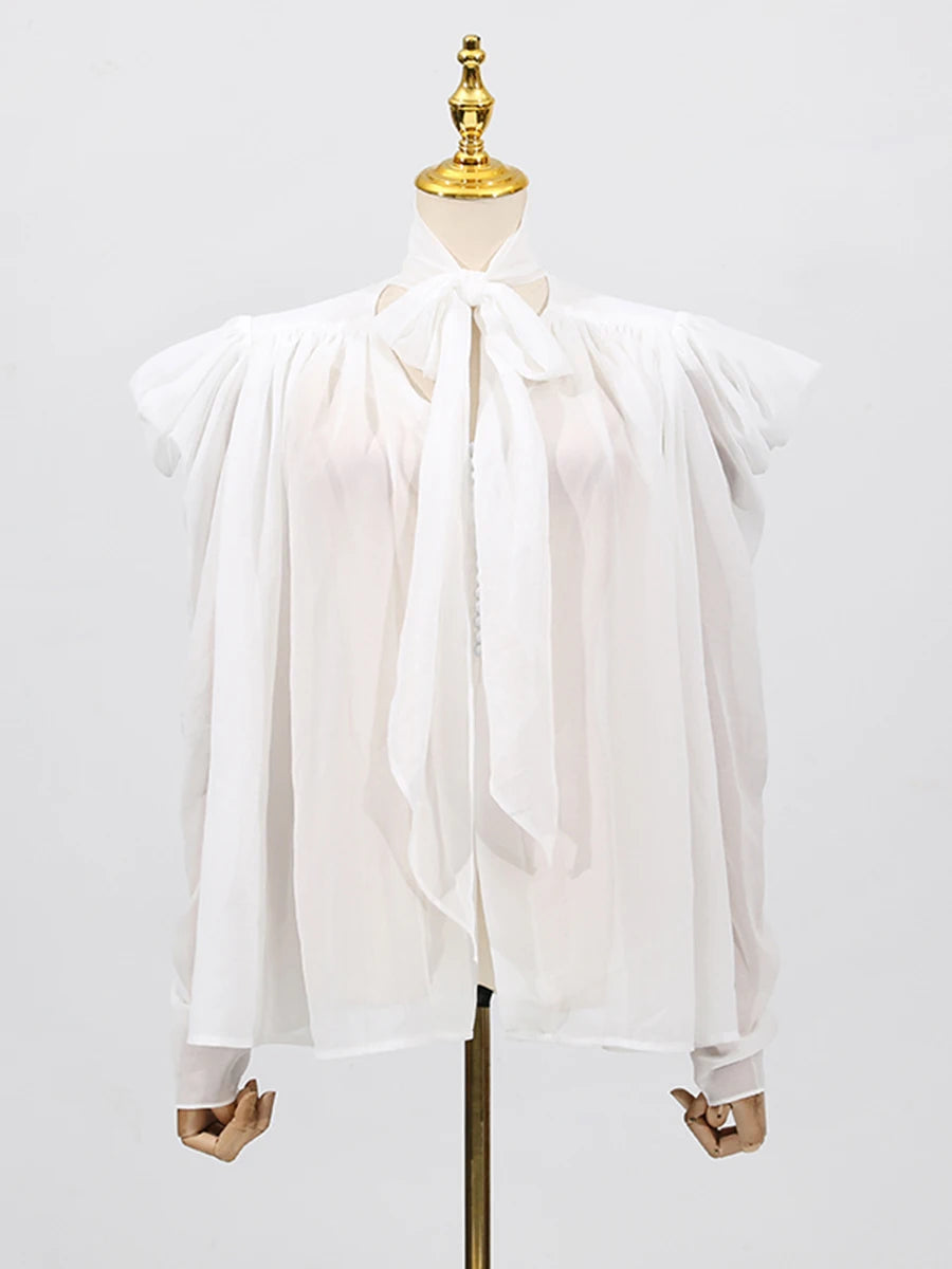 Close-up of the blouse showing folded detailing along the bodice and soft woven texture.