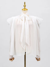 Close-up of the blouse showing folded detailing along the bodice and soft woven texture.