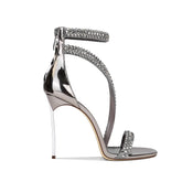 A close-up of the metal and rhinestone detail on the sandal.