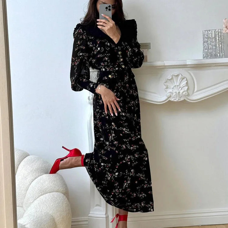 Person wearing a metal button vintage gown in a retro print for spring summer occasions with red high heels in a room with white walls and a fireplace.
