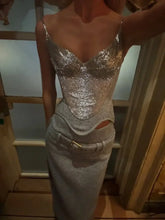 Close-up of a silver metallic sequin corset cami with sweetheart neckline, creating a sculpted waistline under warm indoor lighting.