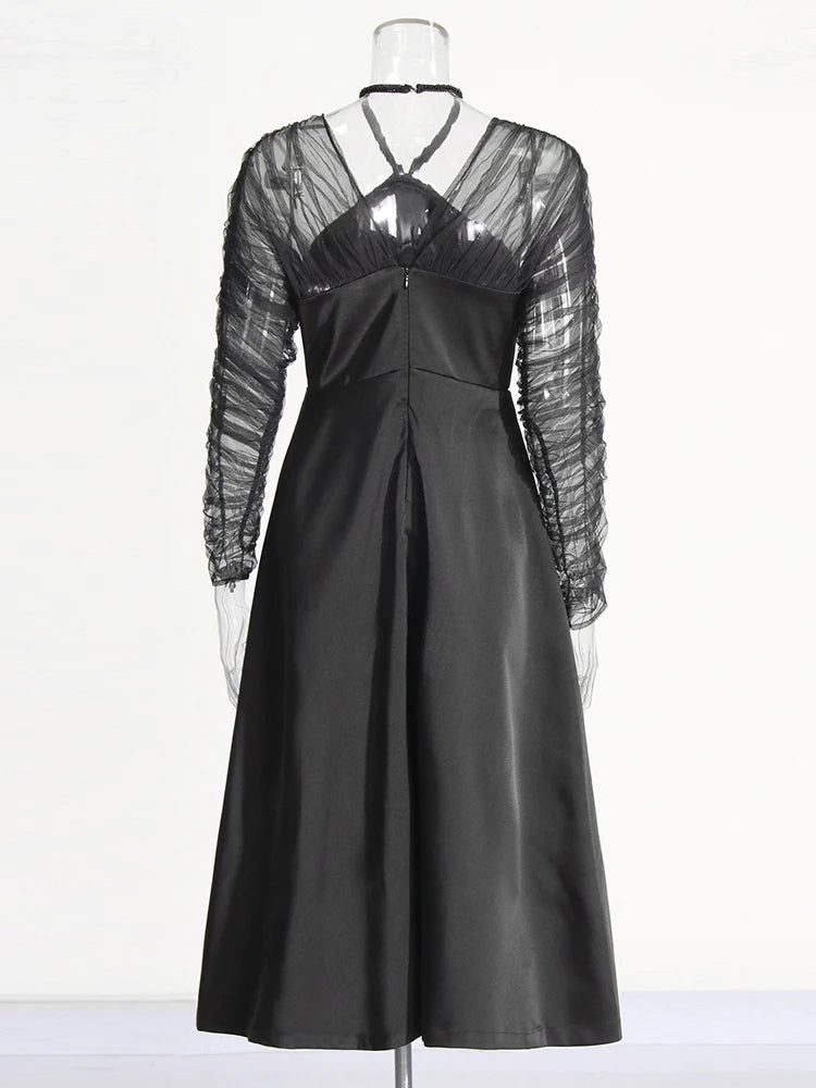 Black dress with sheer sleeves on a mannequin against a white background