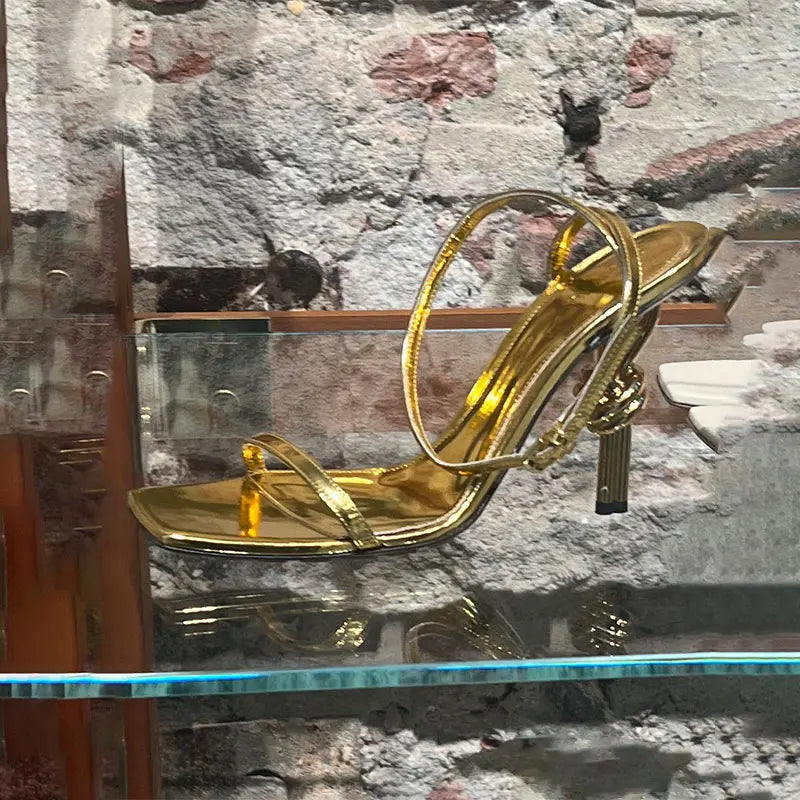 Modern gold strappy shoes with sculptural heel for evening wear