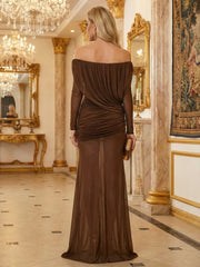 Woman in a brown off-shoulder evening gown standing in an opulent room with gold accents.