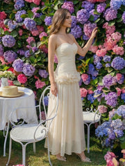 Full-length outdoor view showing the ankle-length hem and floaty skirt, styled with heels beside garden seating for an event look.