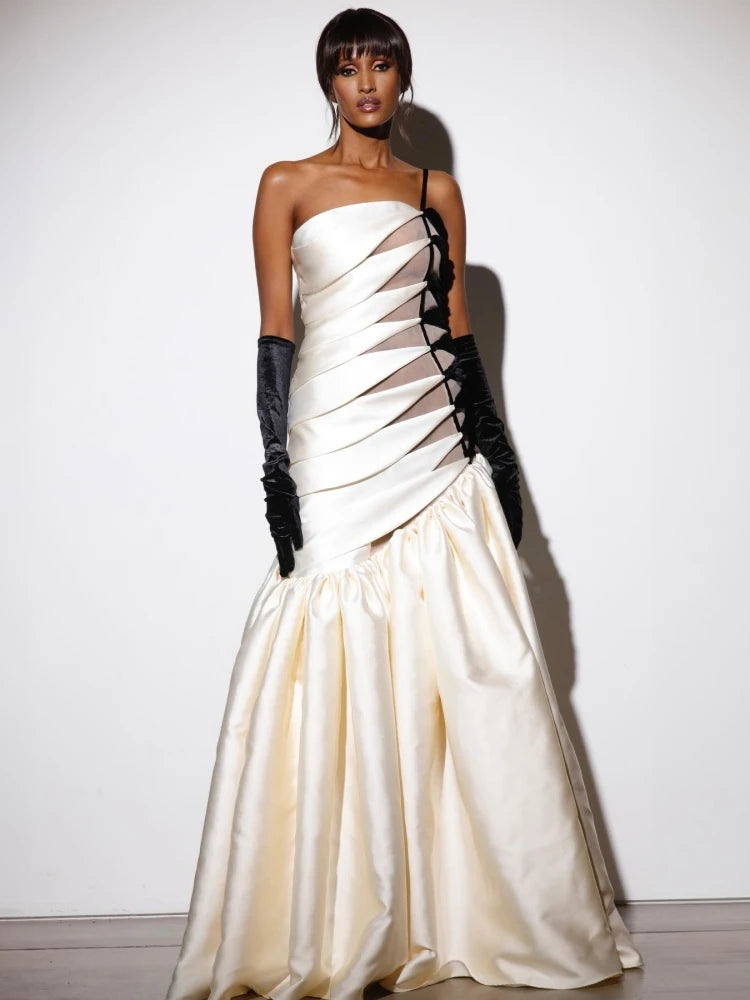 One-shoulder hollow-out white maxi dress with matching gloves styled for galas. Woman wearing a strapless white evening gown with black gloves against a plain background