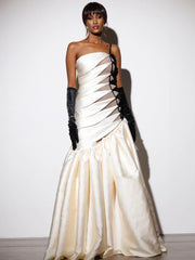 One-shoulder hollow-out white maxi dress with matching gloves styled for galas. Woman wearing a strapless white evening gown with black gloves against a plain background