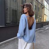 Open-back knit sweater styled for autumn layering in a minimalist room