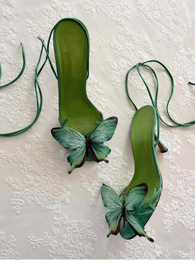 Green high-heeled shoes with butterfly decorations on a textured white background