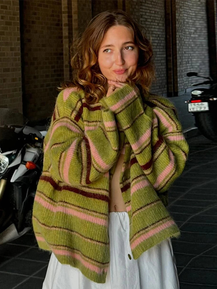 Woman wearing a green and pink striped sweater in an urban setting with motorcycles.