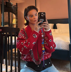 Close detail of the knit texture and tassel edging on a red paisley cardigan, highlighting the patterned weave and soft finish