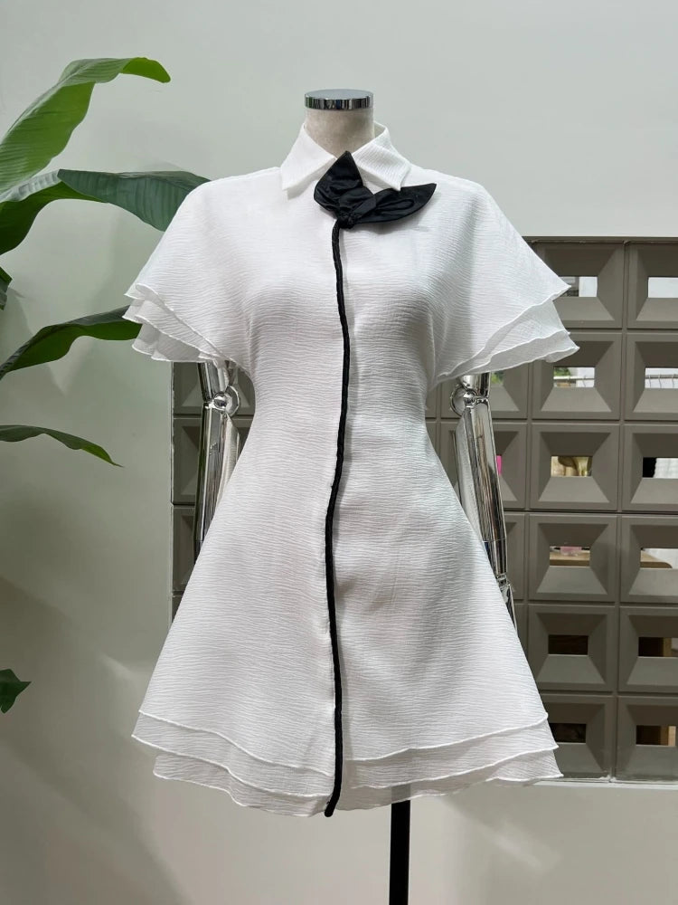 Feminine cocktail mini with contrast edging and fitted waist and black accents on a mannequin against a neutral background