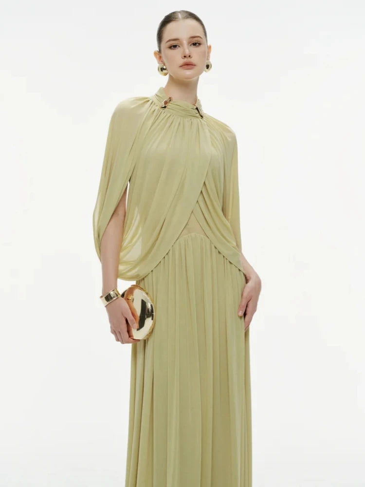 Upper-body detail showing the round neckline with metal pin accent and layered folds that create a sculpted, elegant drape.