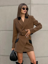 A woman wearing a two-piece patchwork suit set with a short jacket and asymmetrical mini skirt.