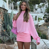Woman in a pink chiffon mini dress with ruched skirt and sheer sleeves”