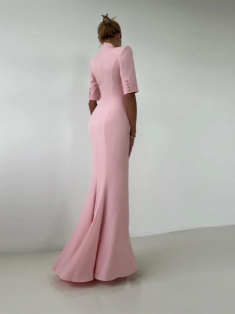 Person wearing a pink evening gown with a plain background