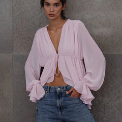 Ruched pink mesh blouse with balloon sleeves and tie front worn by model.