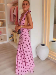Woman in a pink polka dot dress standing in a room with shelves and decor.