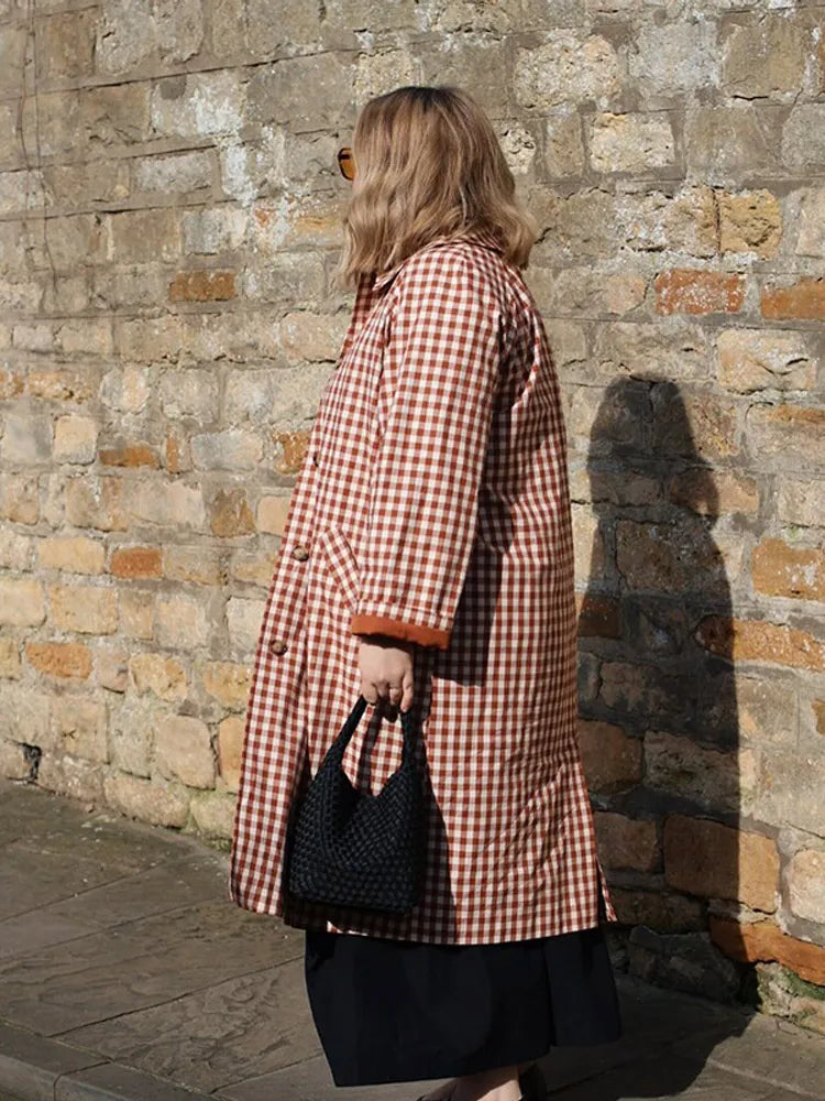 Person wearing a red and white checkered coat against a stone wall.