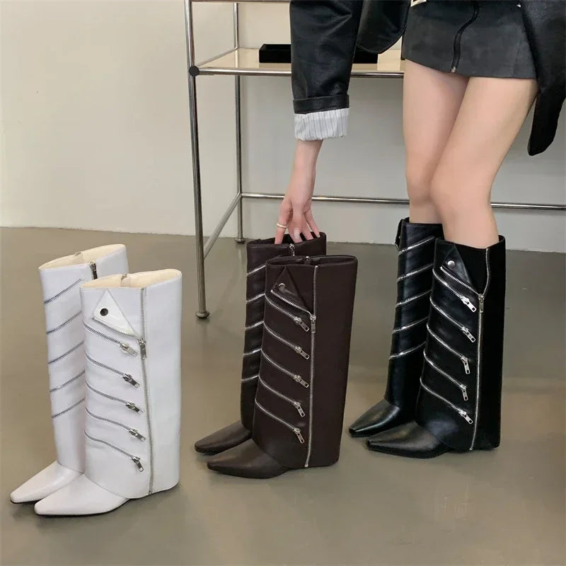 Black and white knee-high boots with zippers on a neutral background