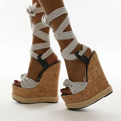 A pair of white platform wedge sandals with an ankle strap.