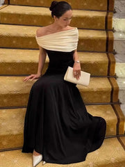 Woman in a black and white evening gown sitting on gold steps.