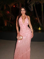 Woman in a plunging neckline sequin gown for a beach event or cocktail night, holding a gold clutch at night.