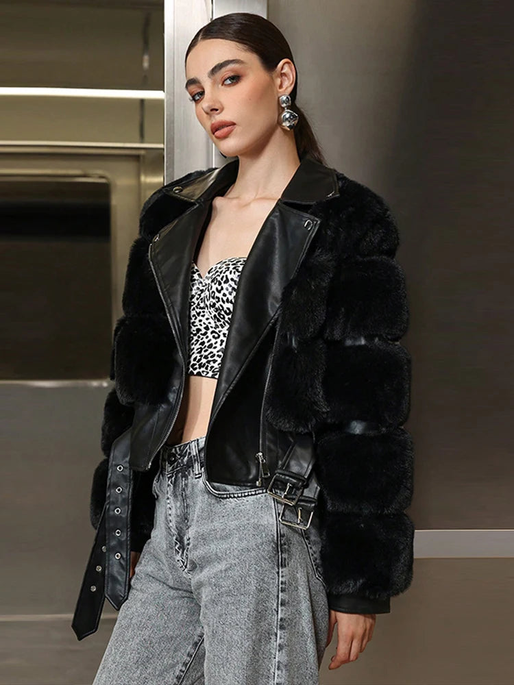 Woman wearing a black fur coat, leopard print top, and gray jeans indoors.