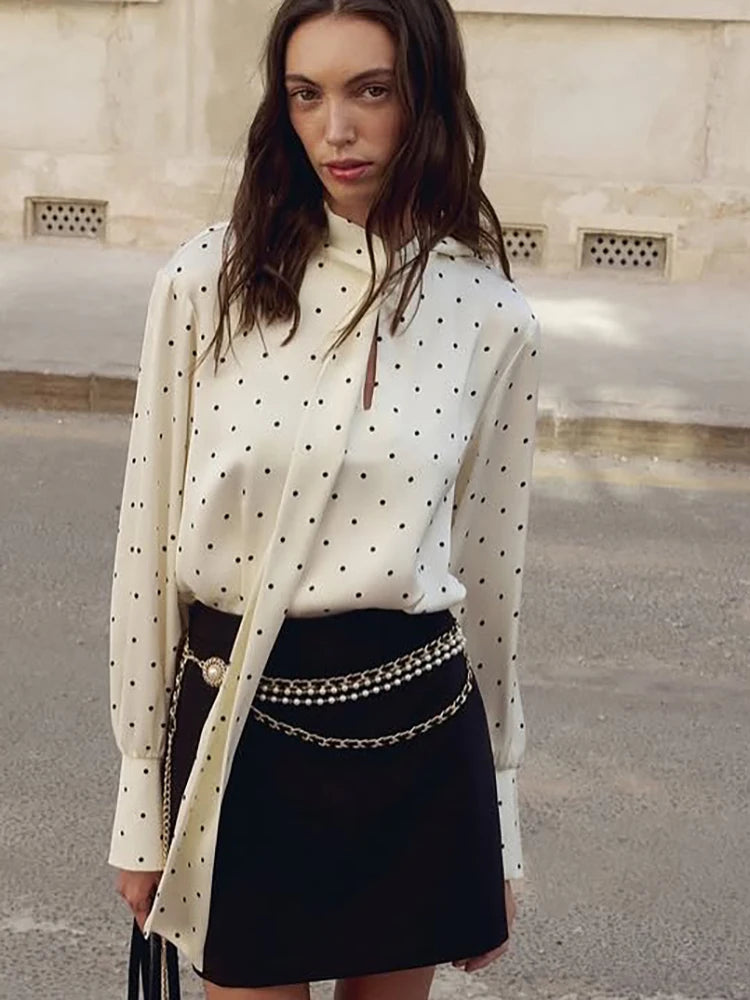 Polka dot button-up blouse styled with metallic chain belt for party look