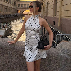 Polka dot halter mini dress styled beside a canal with sunglasses