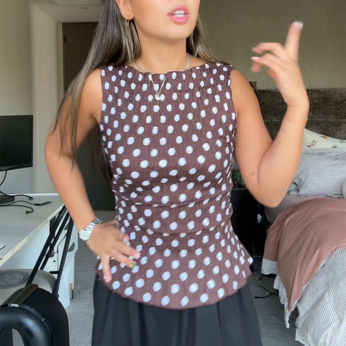 Woman wearing polka dot peplum summer blouse in lightweight fabric in an indoor setting.