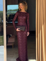 Woman in a burgundy lace dress holding a clutch in an indoor setting.