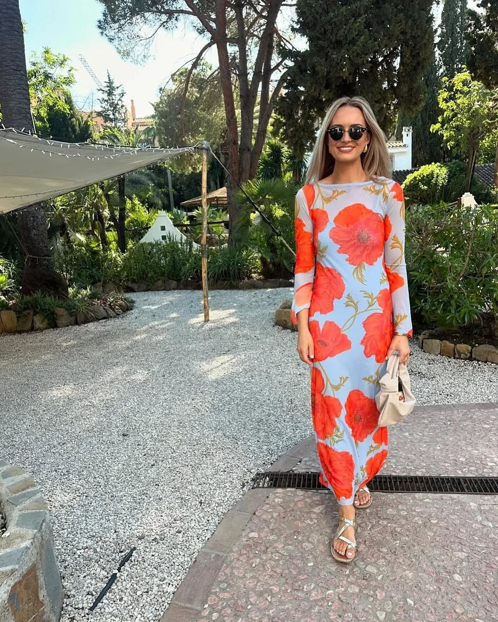 woman in a blue long sleeve maxi dress with red poppy print outdoors