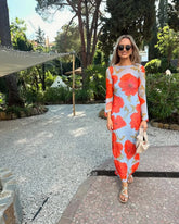 woman in a blue long sleeve maxi dress with red poppy print outdoors