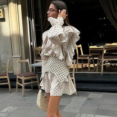 Woman in side view of patterned waist seal cinching a printed summer mini dress with tables and chairs in the background