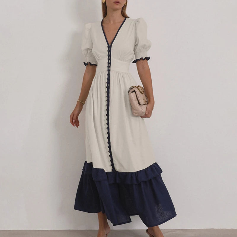 A woman wearing an apricot and navy dress with a flared hem and front slit against a plain background.