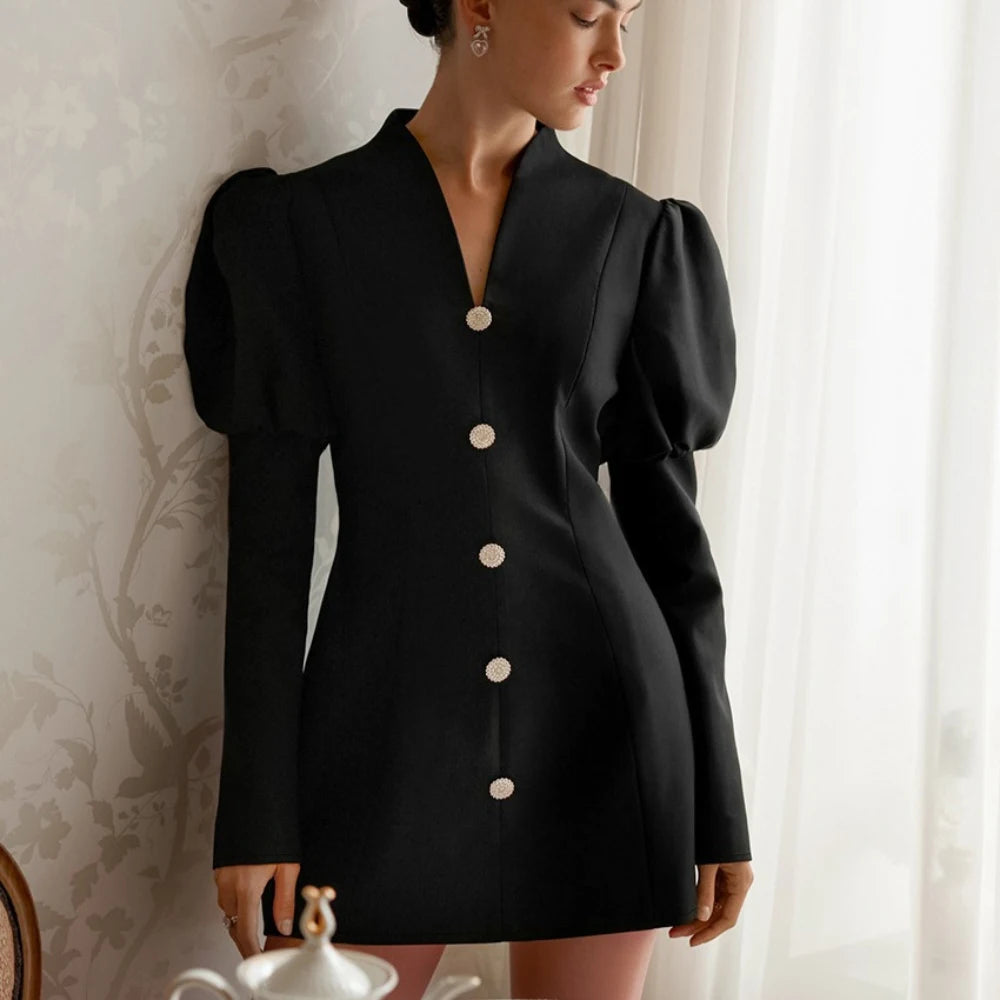 Close-up of puff sleeves and button detailing on a black mini dress.