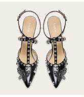 A woman modeling a punk rivet sandal with a butterfly and a thin heel.