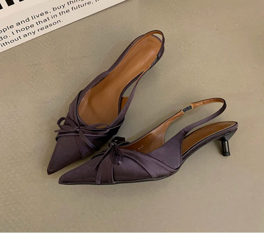 Purple slingback heels with butterfly-knot design on beige surface