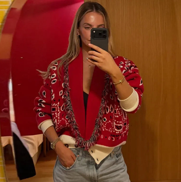 Front view of a red printed V-neck cardigan layered open, showing contrast trim and relaxed knit drape with a clean studio background