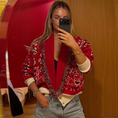 Front view of a red printed V-neck cardigan layered open, showing contrast trim and relaxed knit drape with a clean studio background