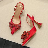“Red satin slingback heels with sequin bow and pointed toe”