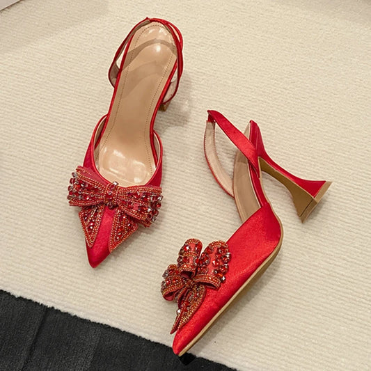 “Red satin slingback heels with sequin bow and pointed toe”