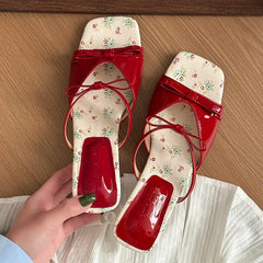 Glossy red wedge heel slides with floral insole on wooden floor