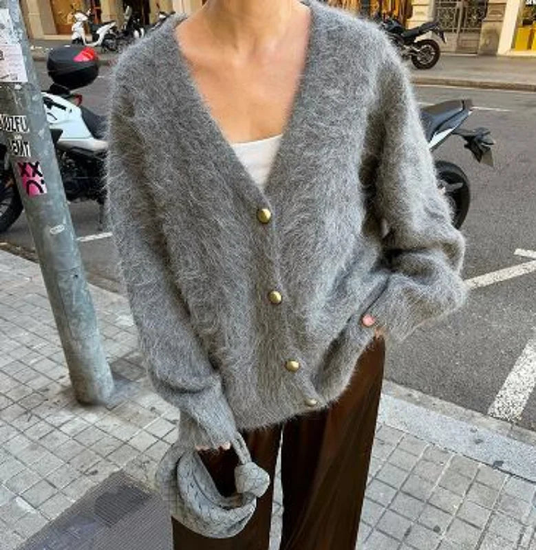 Angled pose in a gray V-neck cardigan showing the relaxed drape through the shoulders and sleeves, styled for an effortless urban outfit.