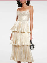 Model wearing a champagne pleated tiered midi dress with rhinestone accents and slim shoulder straps.