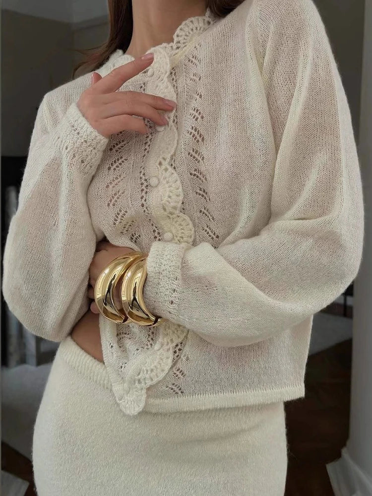 Model wearing a soft knit round-neck cardigan top with pleated detailing, styled with minimal jewellery in a calm indoor setting.